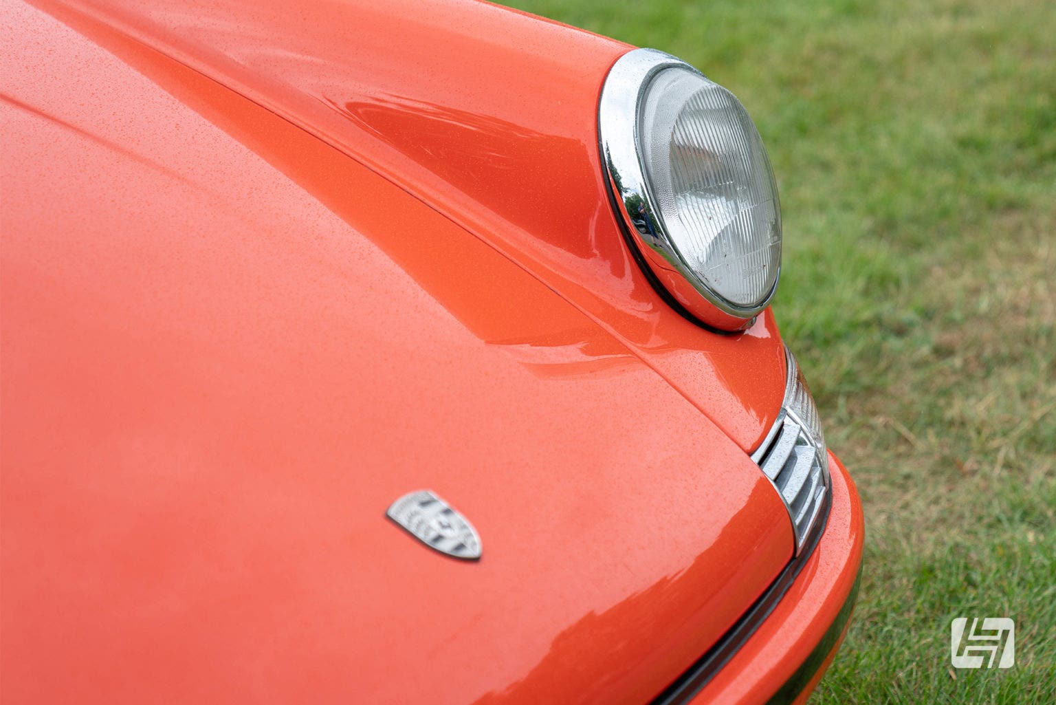 Close up of Porsche badge on bonnet of orange classic Porsche 911