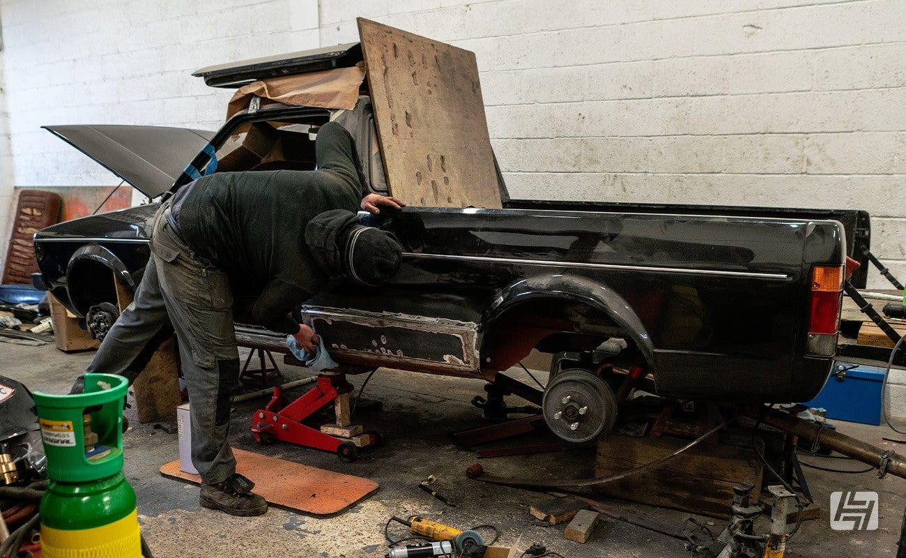 Black VW Caddy jacked up in workshop being worked on by mechanic