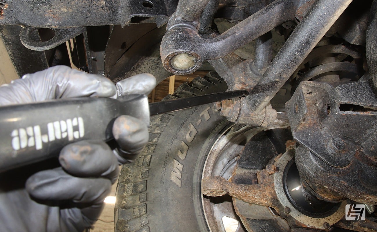 Mechanic points a screwdriver towards a Land Rover Defender panhard rod