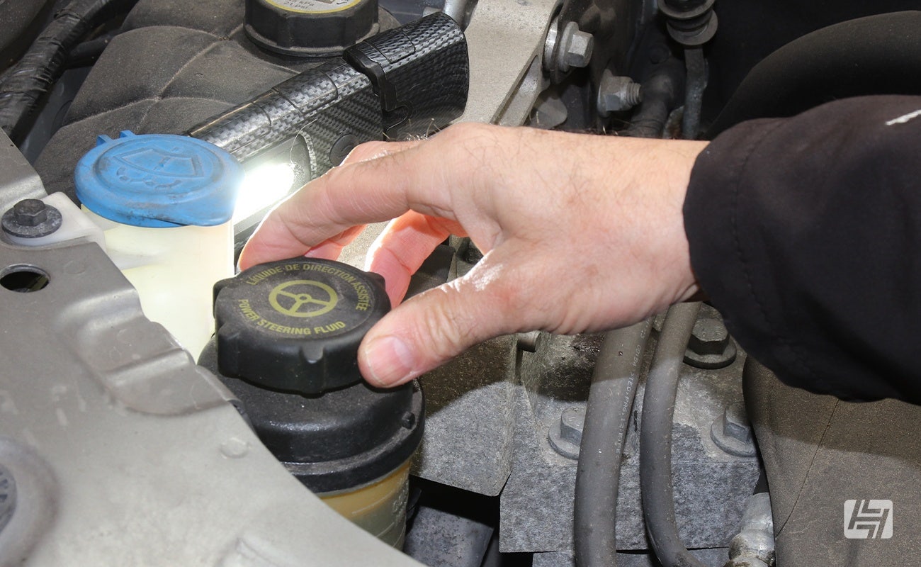 mechanic unscrewing PAS fluid reservoir