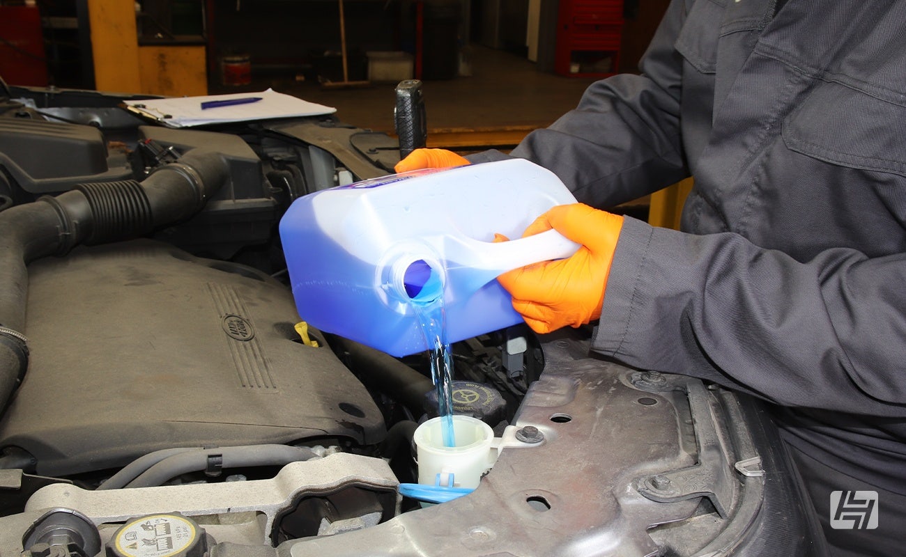 Mechanic pours screen wash into reservoir on Land Rover Freelander 2