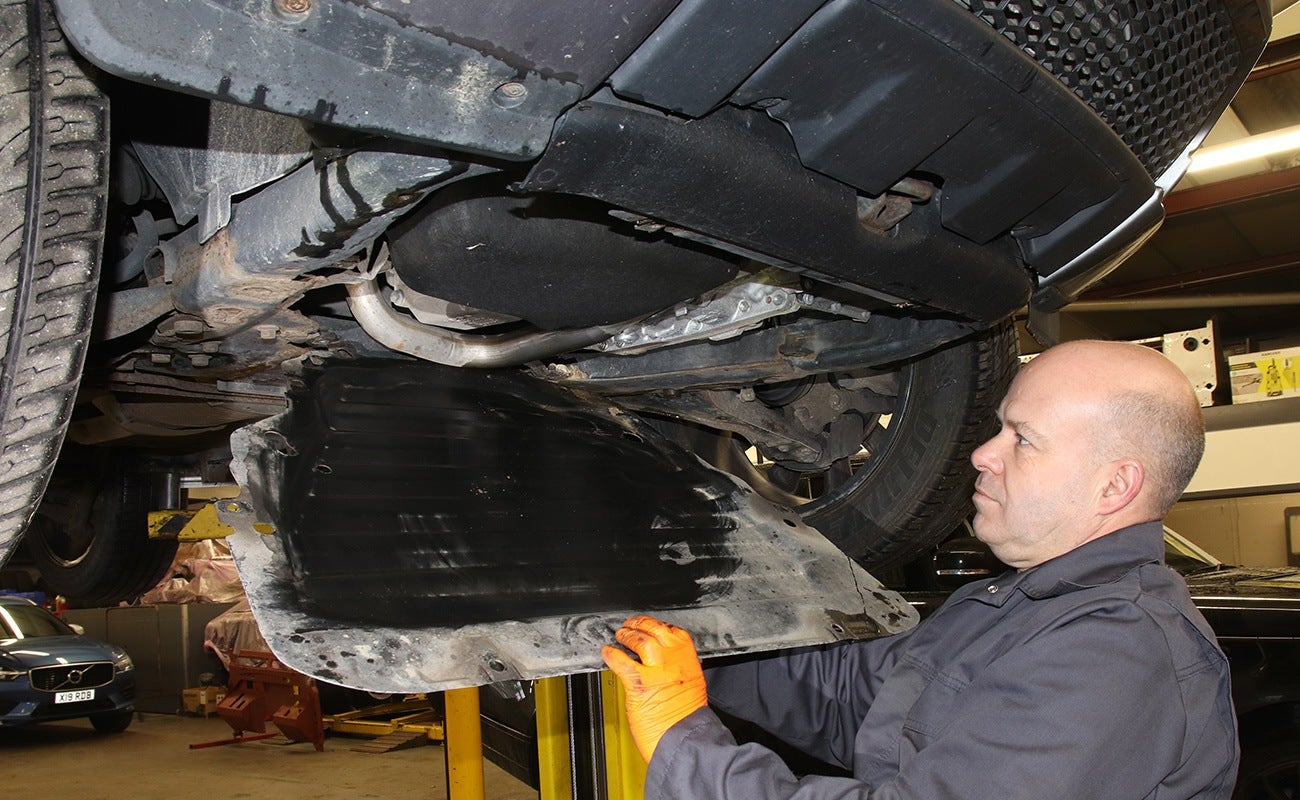 Mechanic removes undertray on Land Rover Freelander 2 to carry out oil change