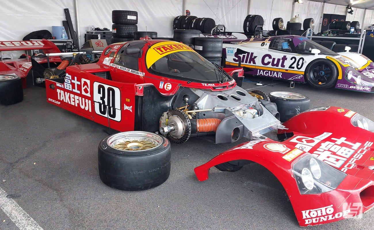Red Porsche 962 race car in paddock with wheels off Le Mans Classic 2023