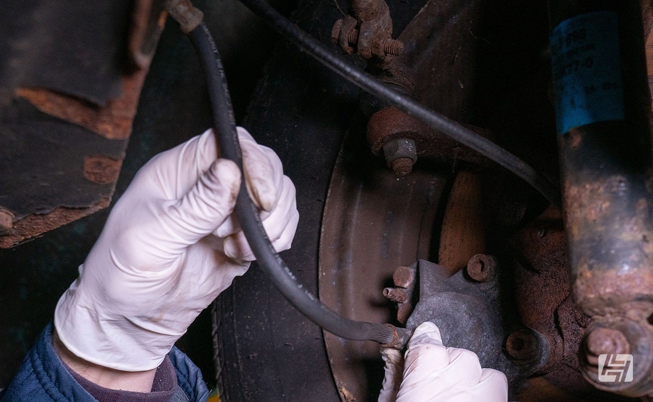 mechanic examines rubber brake hose on VW Beetle