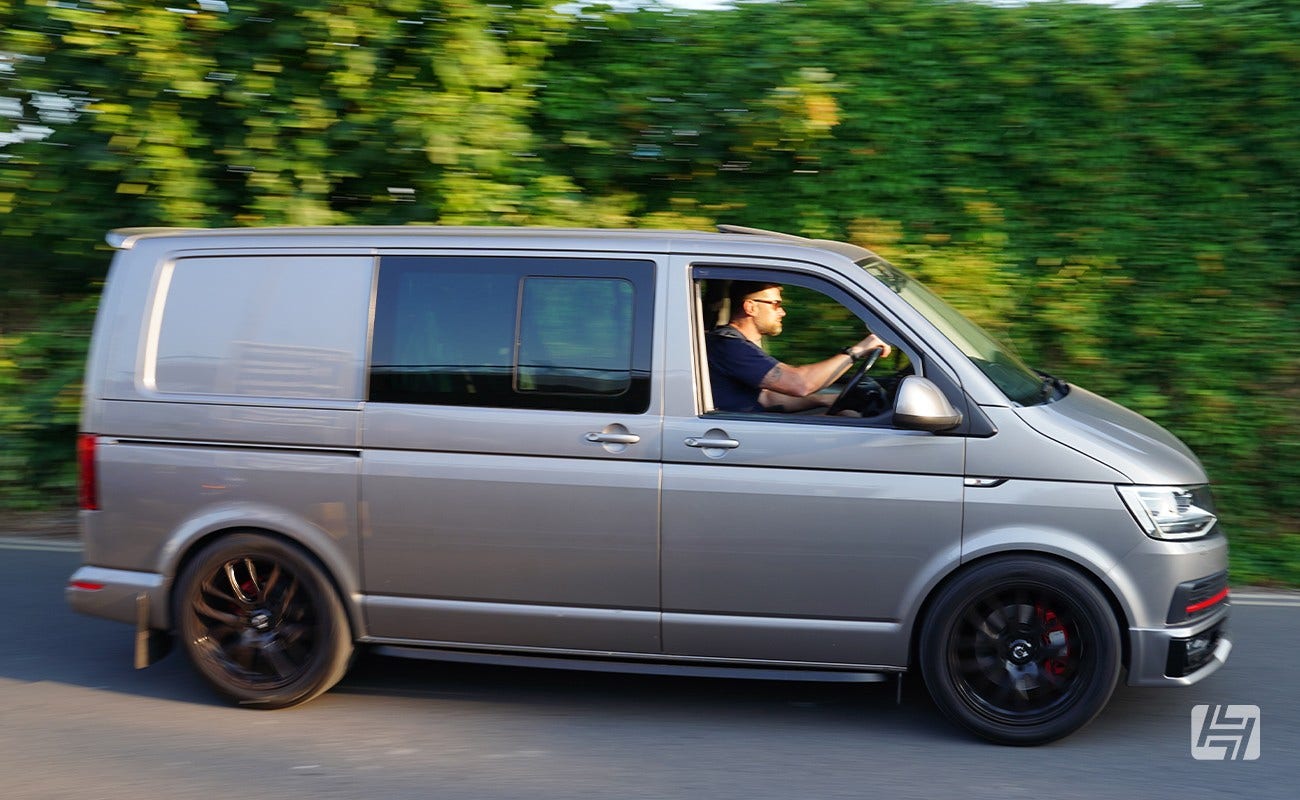 Grey VW T6 with black wheels driving, side shot
