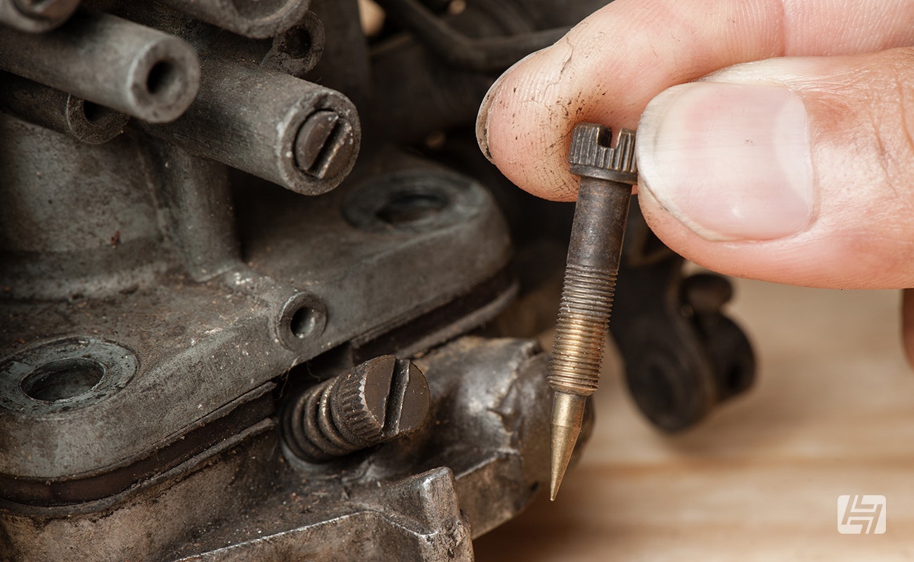 Hand holding carburettor adjustment screw valve